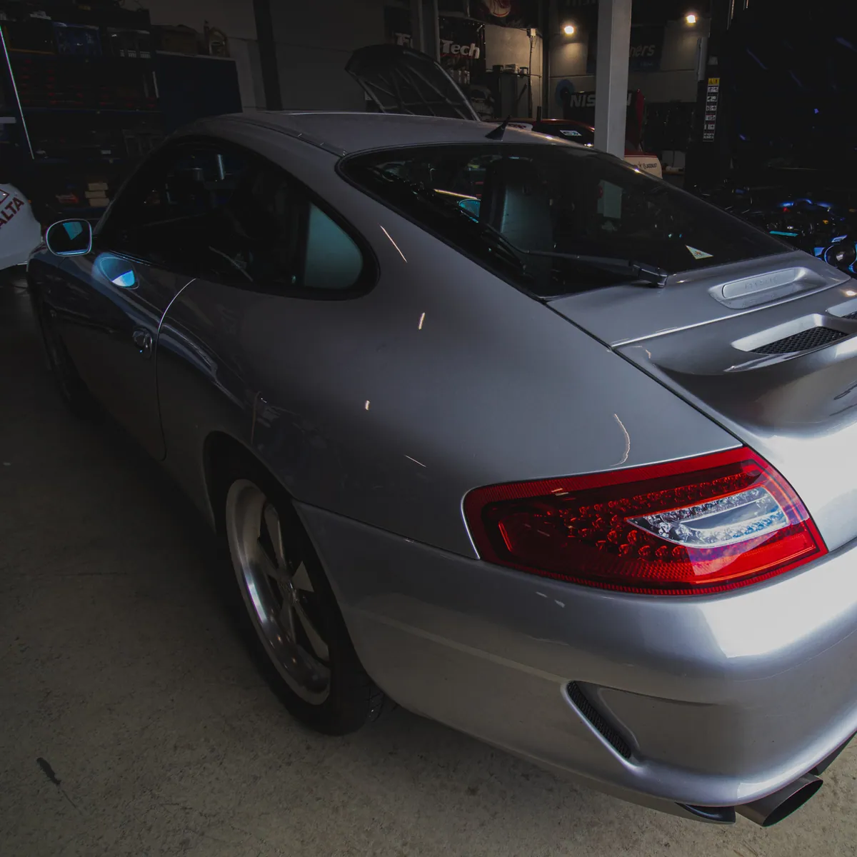 Zilvergrijze Porsche 911 in de werkplaats van VPR-Engineering, met gereedschapskasten op de achtergrond.
