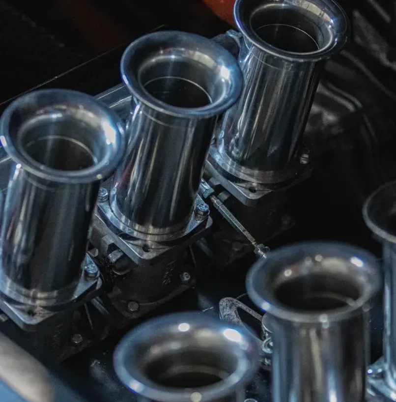 Gepolijste aluminium inlaattrompetten op de individuele smoorkleppen van een racemotor.